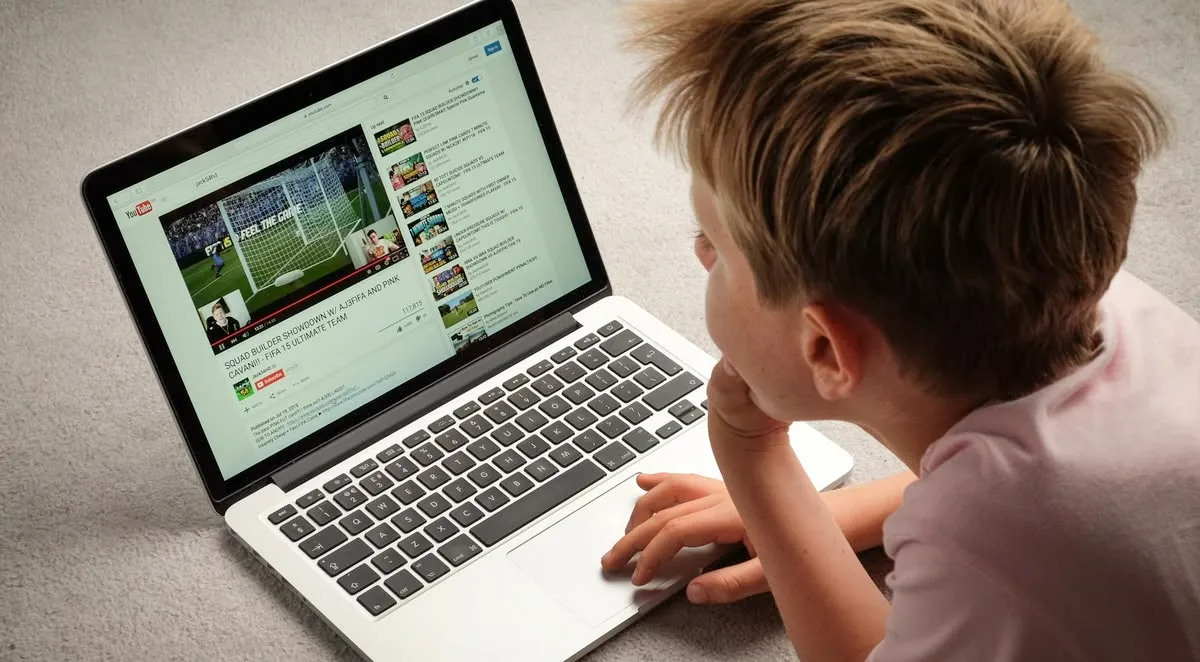 A boy watching a video site on a laptop with a column of recommendations alongside