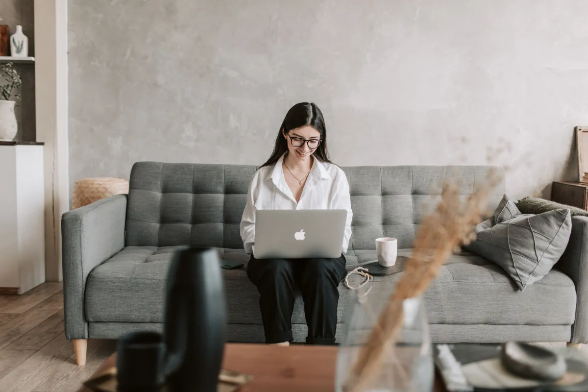 A woman sitting on a sofa using a laptop in a calm living room